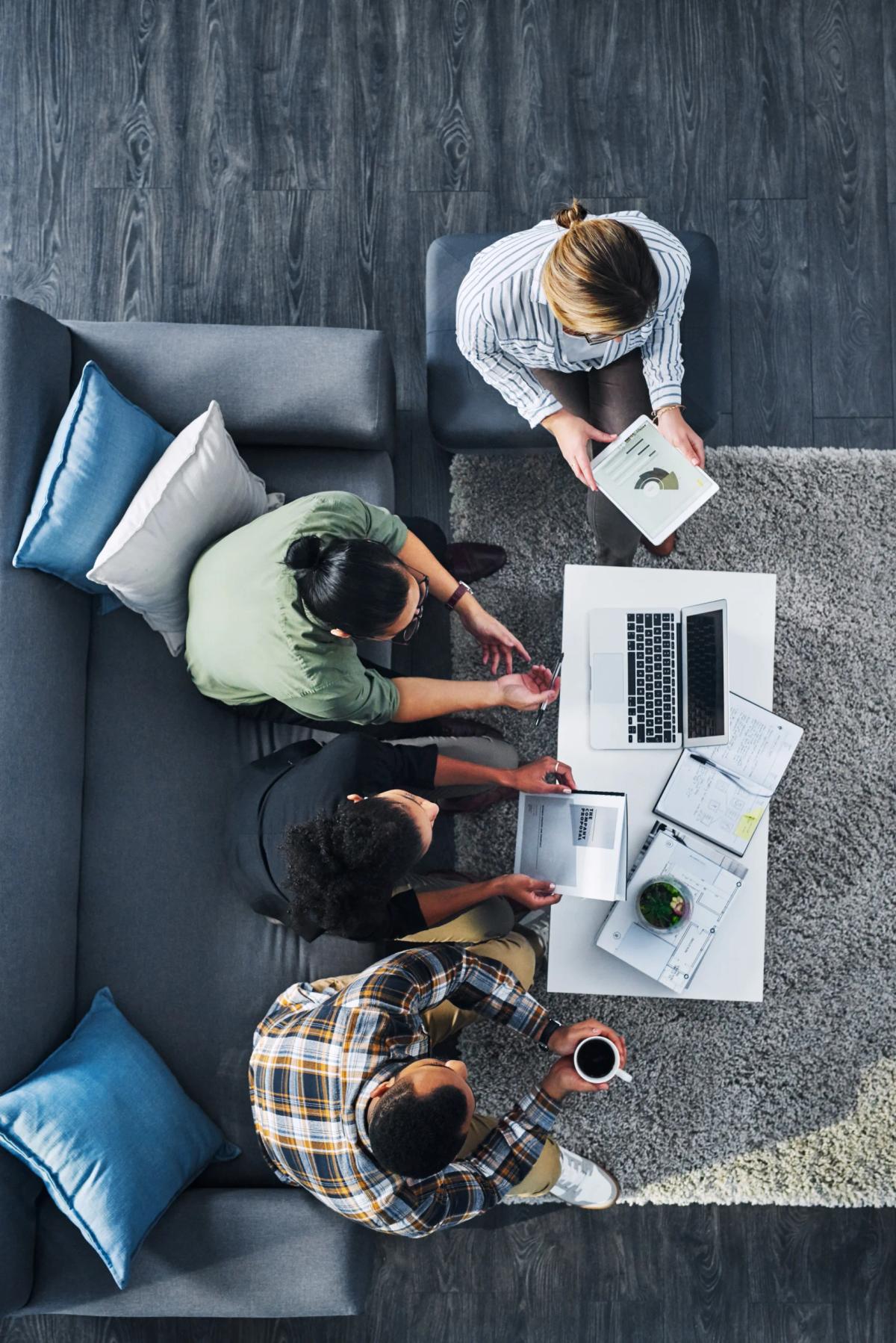 Four people sitting on a couch working with a computer